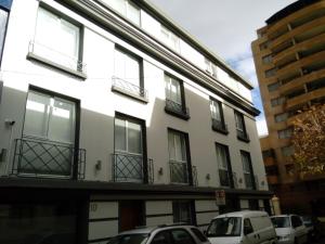 a white building with balconies and cars parked on a street at Hotel Elisa Cole in Santiago