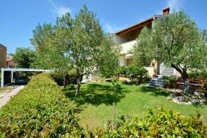 un jardin en face d'une maison arborée dans l'établissement Apartments Andreja, à Kožino