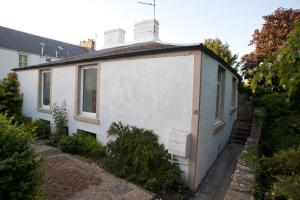 a small white house with a door on the side of it at Maggie's Cottage in Kelso