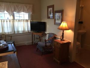 a living room with a lamp and a chair and a television at The Holiday House Inn & Motel in Scarborough +56 photos