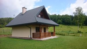 una piccola casa con un tetto nero su un campo di Domek u Bigola a Polańczyk