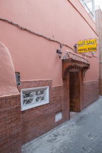 un bâtiment en briques avec une porte et un panneau sur celle-ci dans l'établissement Hotel Zaitoune, à Marrakech