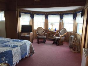 a bedroom with a bed and two chairs and a desk at The Holiday House Inn & Motel in Scarborough