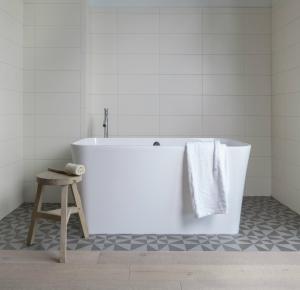 a white bath tub in a bathroom with a stool at Boro Hotel in Queens