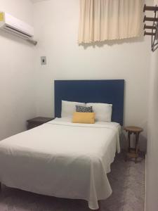 a bedroom with a white bed with a blue headboard at Hotel Florida in Villahermosa