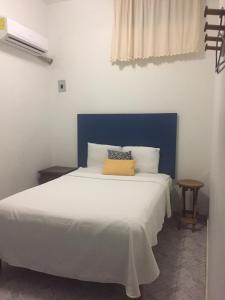 - une chambre avec un lit blanc et une tête de lit bleue dans l'établissement Hotel Florida, à Villahermosa