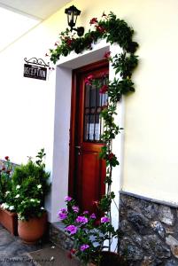 a red door with flowers on a white building at Filoxenia Studios in Galaxidi