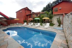 uma piscina com cadeiras e guarda-sóis ao lado de uma casa em Pousada Recanto em Pirenópolis