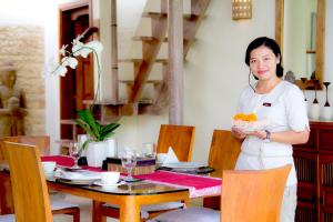 a woman standing in a restaurant holding a bowl of food at Mayana Villas in Canggu +90 photos