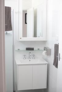 Baño blanco con lavabo y espejo en Otway Gate Motel en Colac