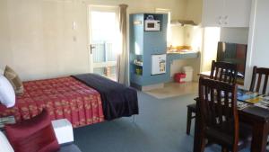 1 dormitorio con cama, mesa y cocina en Bella Tuscany Motor Lodge, en Napier