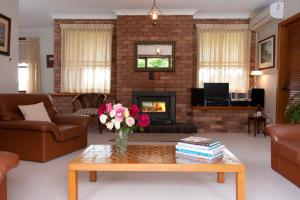 a living room with a fireplace and a vase of flowers at Clifton Gardens Bed & Breakfast - Orange in Orange