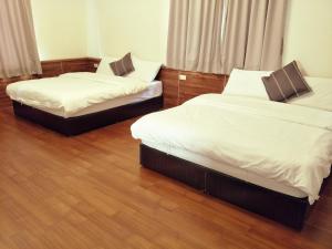 two beds in a room with wood floors at Lu He Feng Homestay in Luodong