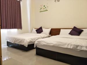 two beds sitting in a room with a window at Lu He Feng Homestay in Luodong