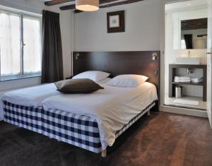 a bedroom with a large bed with white sheets and pillows at Hotel Hoeve de Plei in Mechelen