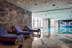 un vestíbulo con piscina y sillas azules en Minyoun Chengdu Dongda Hotel, en Chengdú