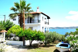 a white house with a palm tree and a boat at Villa Evi in Ammouliani