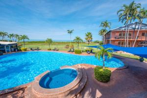 a large swimming pool with a palm tree in front of a building at Moonlight Bay Suites in Broome