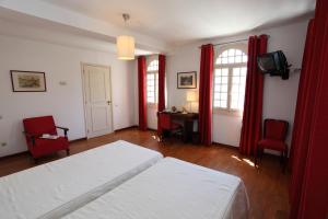 a bedroom with a white bed and red curtains at INATEL Palace S.Pedro Do Sul in Termas de Sao Pedro do Sul