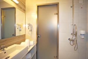 a bathroom with a shower and a sink and a mirror at Astron Suites & Apartments in Kos