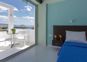ein Schlafzimmer mit einem Bett und einen Balkon mit einem Tisch und Stühlen in der Unterkunft Asteria Hotel in Tolo