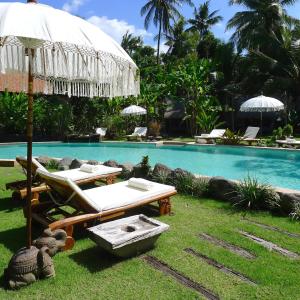 - Piscina con mesa, sillas y sombrilla en Desa Saya Eco Luxury Resort & Spa, en Tejakula