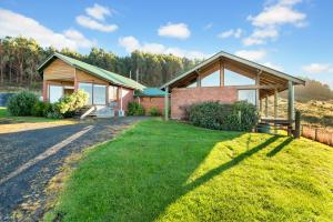 a house that is in the middle of a grassy area at Apollo Panorama Guesthouse in Apollo Bay