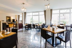 um restaurante com mesas, cadeiras e janelas em Michels Hanseatic Hotel Norderney em Norderney