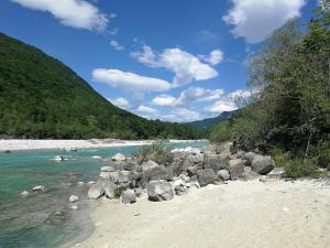 a beach with rocks and water and a mountain at Hiša Kranjc in Kobarid