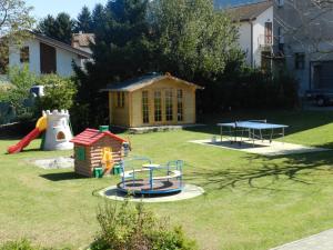 a yard with a playground with a house and a table at Residence Girasole Casa Rossa A in Colico