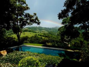 a pool with a rainbow in the background at Riverbend Suite Rooms in Rosebank