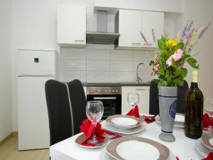 a kitchen with a table with wine glasses and flowers at Apartments Vesela in Janjina