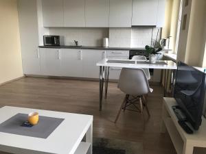 a kitchen with white cabinets and a table and a chair at Gina's apartment Partizanu g in Kaunas