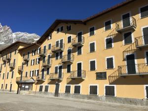 um edifício amarelo com varandas e montanhas ao fundo em Residence Redicervinia em Breuil-Cervinia