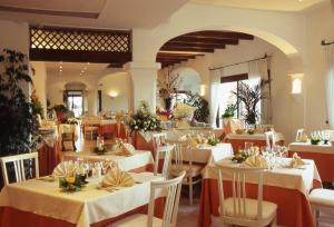 un restaurante con mesas blancas y sillas con flores. en Hotel Stelle Marine en Cannigione