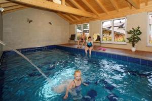 two girls playing in a swimming pool at Berghof Pension und Ferienwohnungen in Bischofsmais