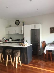 a kitchen with a counter and stools and a refrigerator at Seaside Home in Melbourne