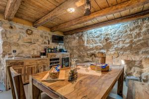 een keuken met een houten tafel en een stenen muur bij Modern and Cozy little House Mia in Dugopolje