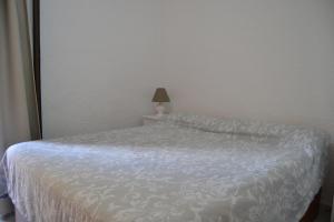 - une chambre avec un lit doté d'une couverture blanche et d'une lampe dans l'établissement California 3 LOCDENIA, à Miraflor