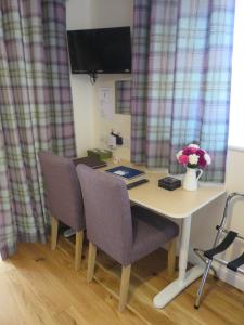 un escritorio con 2 sillas y una mesa con flores. en Apple Tree Corner Apartment en Yate