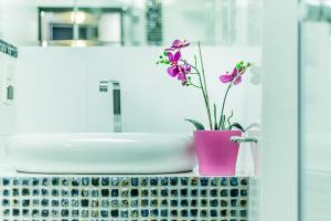 a bathroom counter with a sink and a vase with flowers at Angel City Center Krakow Aparthotel in Krakow