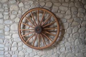 una rueda de carruaje de madera sentada en un suelo de piedra en Casa Rural La Vall del Cadi, en La Seu d'Urgell