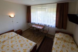 una stanza con due letti, un tavolo e una finestra di Pas Roma a Šventoji