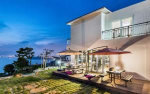 a house with a deck with tables and umbrellas at Yeosu Blooming Pension in Yeosu