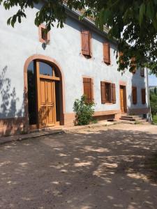 un edificio blanco con puertas y ventanas de madera en Le Vieux Ruisseau, en Lapoutroie