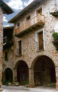 un antiguo edificio de piedra con 2 balcones. en Apartaments Plaça Major, en Santa Pau