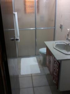 uma casa de banho com um chuveiro, um WC e um lavatório. em Hotel Xapuri em Peruíbe