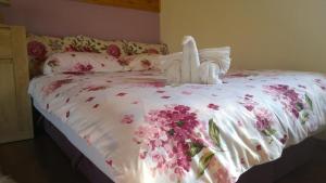 a bed with a white comforter with flowers on it at Apartment Holiday - River view beside Pyramid in Visoko