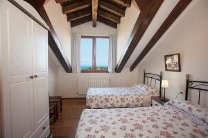 1 dormitorio con 2 camas y ventana en Alojamiento Turístico El Castro en La Revilla