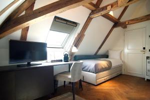 a bedroom with a bed and a desk with a television at The Bolster in Amsterdam